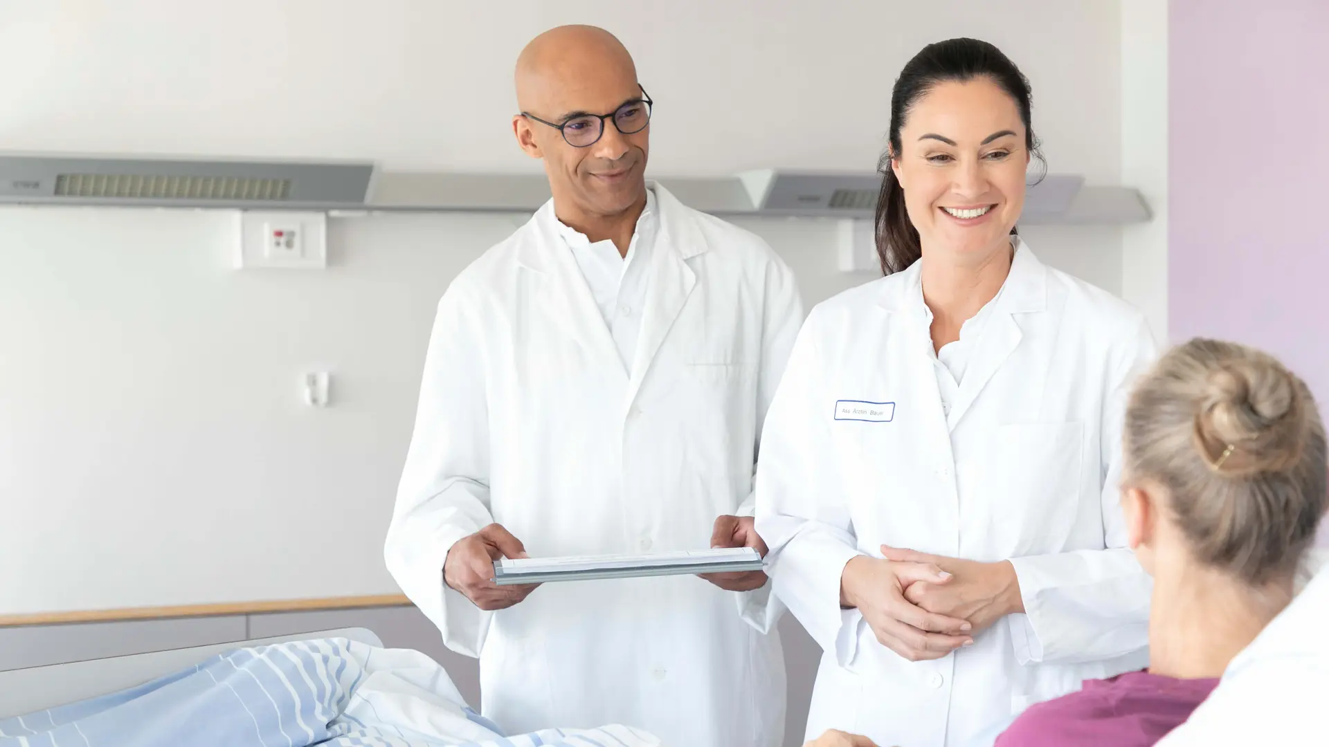 Zwei Ärzte unterhalten sich mit einer Patientin im Bett