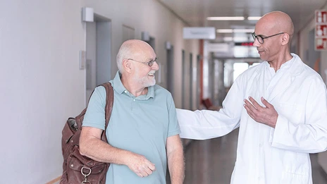 Ein Arzt verabschiedet einen Patienten nach einem erfolgreichen Eingriff. 