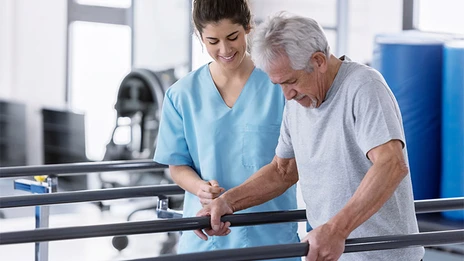 Ein älterer Patient während seiner Therapie zur Wiederherstellung der Bewegungsfunktion.
