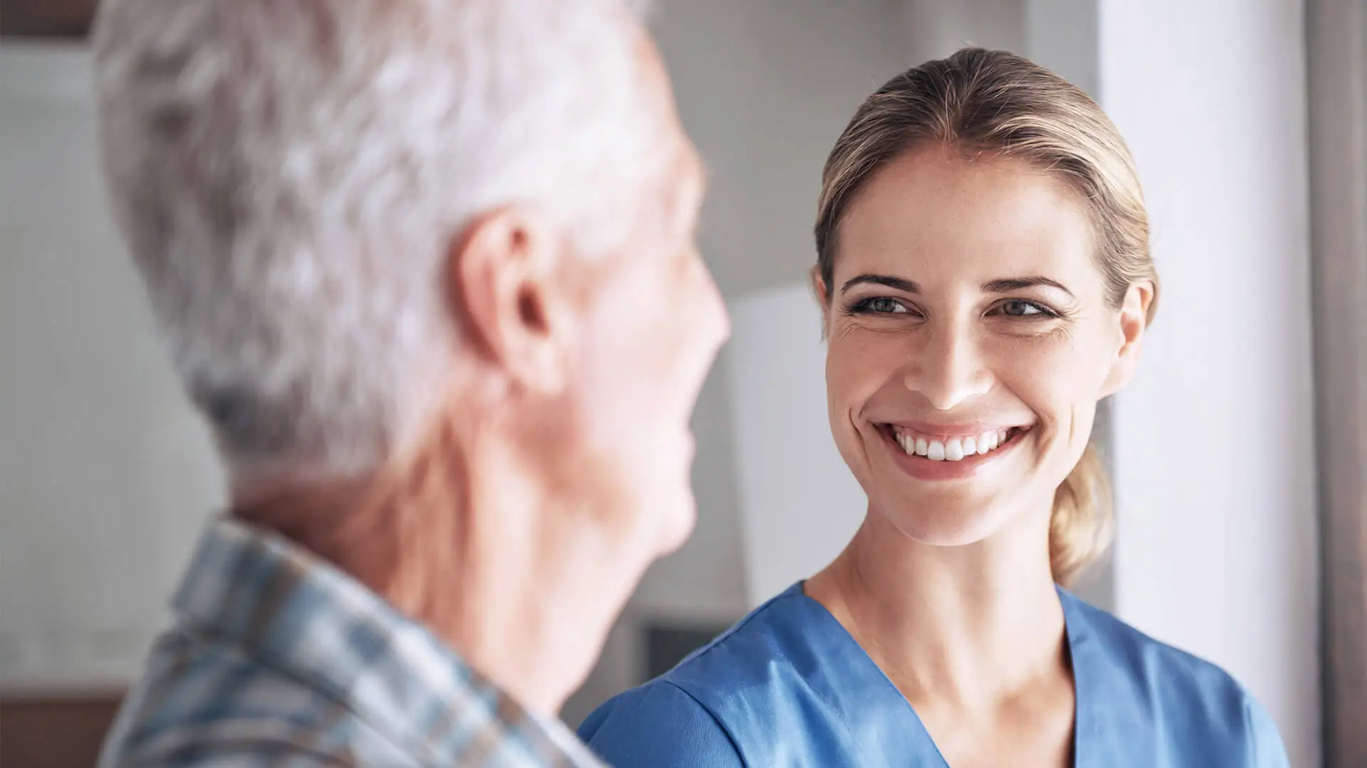 Eine Logopädin lächelt ihren Patienten freundlich an.