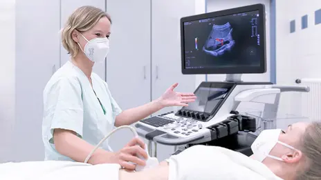 Eine Mitarbeiterin der Gastroenterologie für eine Ultraschalluntersuchung am Bauch eines Patienten durch.